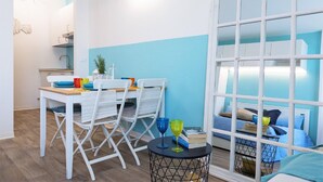 A compact living space with a dining area, kitchenette, and a bed with a view.