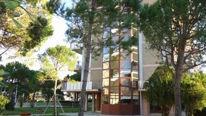 A multi-story building with a modern architectural design, surrounded by trees and a well-maintained lawn.