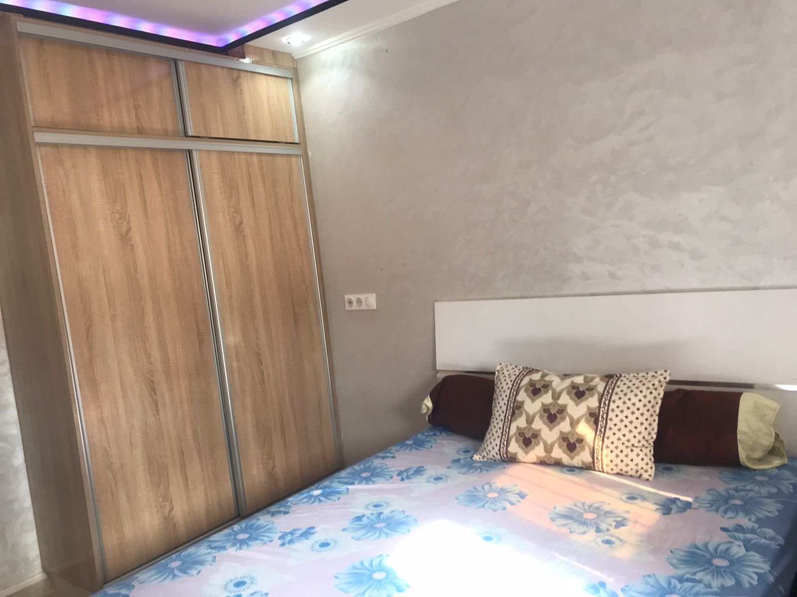 A bedroom with a bed, a wardrobe, and a headboard.