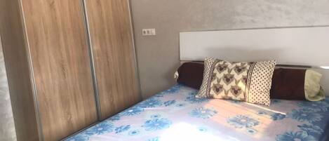 A bedroom with a bed, a wardrobe, and a headboard.