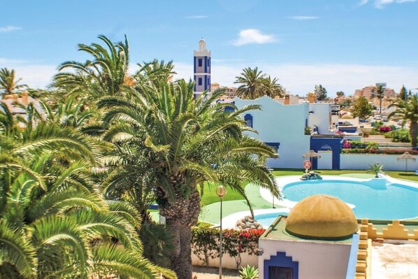 A resort with palm trees, a swimming pool, and a tower.