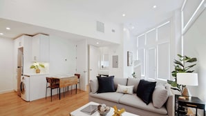 Ein moderner Wohnraum mit Sofa, Couchtisch und Essbereich mit Tisch und Stühlen.