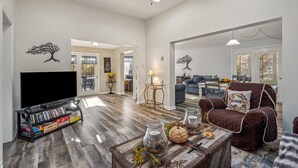 Ein geräumiges Wohnzimmer mit Flachbildfernseher, Bücherregal und Couchtisch mit Dekoration.
