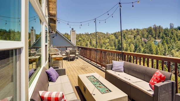 A deck with outdoor furniture, a fire feature, and a view of a forested area. - Lake Arrowhead Getaway with Decks + Game Room! (Lake Arrowhead)