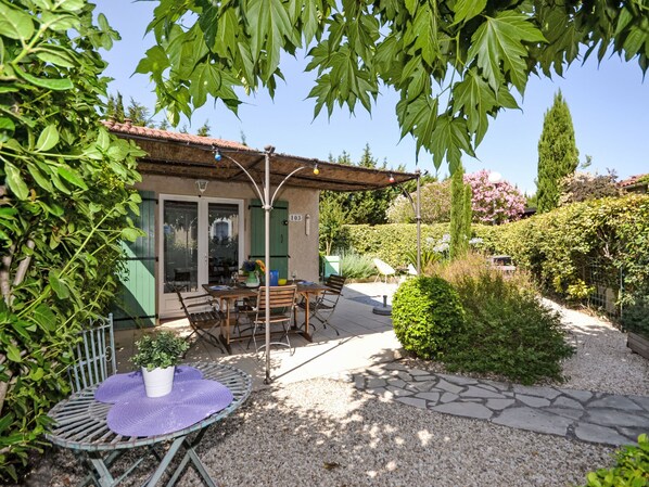 A patio area with a table and chairs, a potted plant, and a stone pathway.