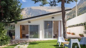 A modern house with a patio, a stone pathway, and a view of mountains.