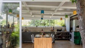 A modern kitchen with a wooden dining table, built-in appliances, and large windows.