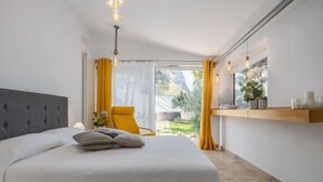A bedroom with a bed, a chair, a window, and a shelf with items.