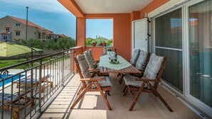 Un balcón con mesa y sillas, una piscina y vistas a casas vecinas.