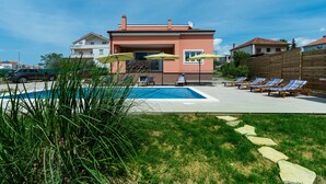Un edificio residencial con piscina, mobiliario exterior y patio cercado.