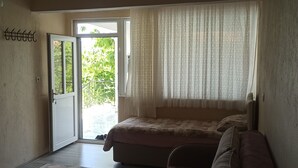 Une chambre à coucher avec un lit, une fenêtre avec des rideaux, une porte et un porte-manteau fixé au mur.