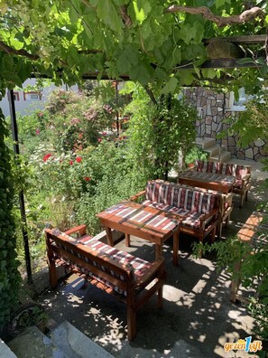 An outdoor seating area with wooden furniture and a stone wall backdrop. - Salda Gölü Kumsalda Apart Pansiyon (Salda)