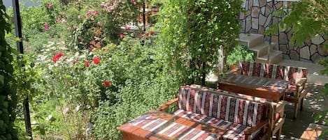 Un área de estar al aire libre con mobiliario de madera y un fondo de pared de piedra.