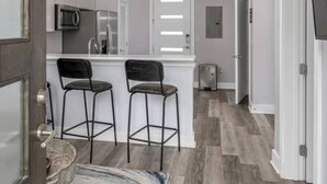 A modern kitchen with a central island, two bar stools, pendant lighting, and a microwave. - 1st Floor Condo No Steps - 2 miles to Downtown (Nashville)
