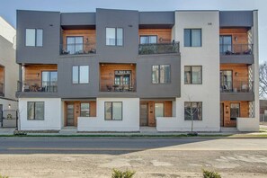 Ein modernes Mehrfamilienhaus mit Balkonen, großen Fenstern und einer Fassade aus Holz und Metall.