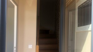 Eine Treppe führt zu einer oberen Etage, eine Tür mit dekorativer Verzierung und ein Lichtschalter an der Wand.