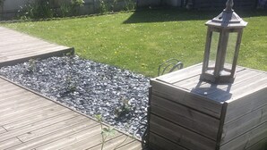 Eine Holzterrasse mit einem Blumentopf und einer Laterne.