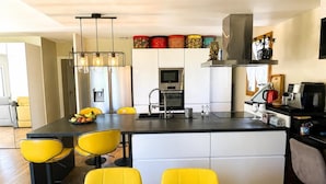 A modern kitchen with a central island, yellow chairs, and a dining table with heart-shaped decorations. - Villa with private pool 🌿 3 bedrooms - near beaches & center - absolute calm (Cavalaire-sur-Mer)