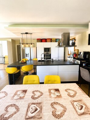 Une cuisine moderne dotée d’un îlot central, de chaises jaunes et d’une table à manger agrémentée de décorations en forme de cœur.