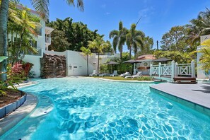 Relax by the serene pool surrounded by lush greenery and tropical plants.
