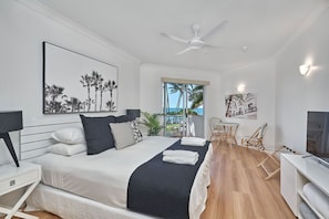 Relax in this serene bedroom with a large bed, ceiling fan, and ocean views through the large window.