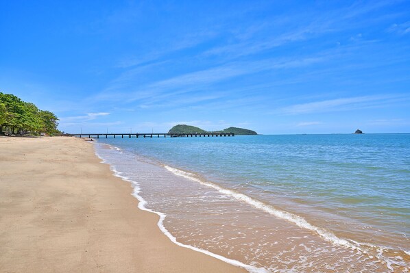 Enjoy a tranquil beach experience with a picturesque pier leading to a lush island.