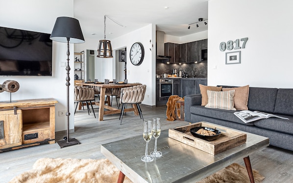 Uma sala de estar moderna com um sofá, uma mesa de centro e uma área de jantar com cadeiras e uma mesa.