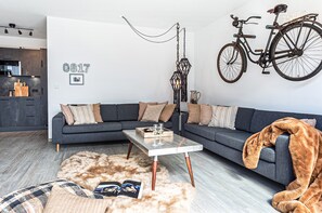 Uma sala de estar moderna com um sofá cinzento, uma mesa de centro e uma bicicleta grande fixada na parede.