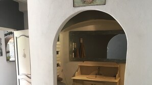 Kapea käytävä johtaa kylpyhuoneeseen, jossa on pesuallas ja hyllyjä.