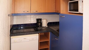 A compact kitchen with wooden cabinets, a microwave, a coffee maker, and a dishwasher. - Ski-in/Ski-out Apartment with Pool (6 pers) - Les Orres 1800 (Les Orres)