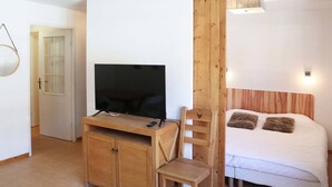 A bedroom with a bed, a TV on a wooden stand, a chair, and a wardrobe. - Ski-in/Ski-out Apartment with Pool (6 pers) - Les Orres 1800 (Les Orres)