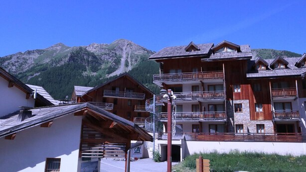 A mountain lodge with wooden architecture, balconies, and a view of a mountain. - Ski-in/Ski-out Apartment with Pool (6 pers) - Les Orres 1800 (Les Orres)