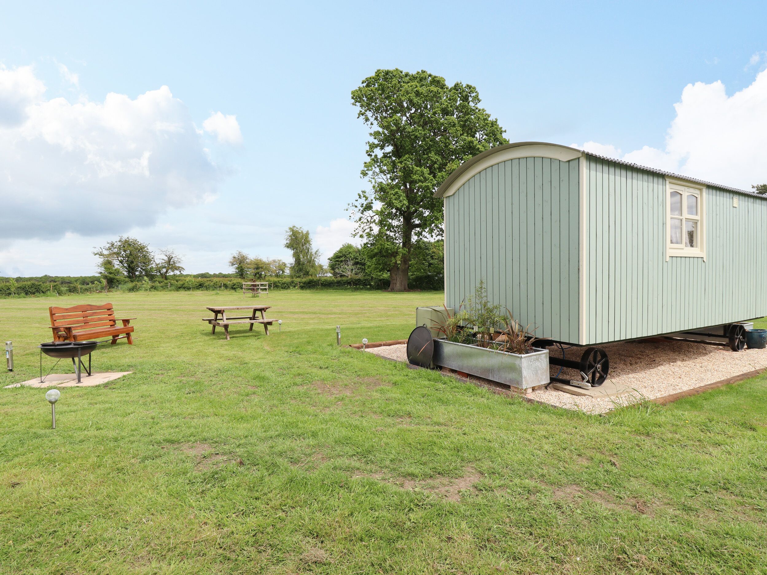 Une maison mobile avec un petit jardin, une table de pique-nique et un banc.