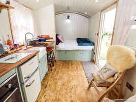 Habitación compacta con kitchenette, una cama con manta azul, un sillón mullido y vistas al exterior.