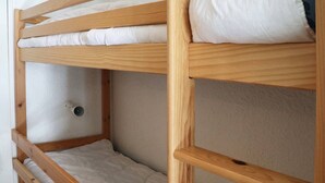 A bunk bed with a wooden frame and white bedding.