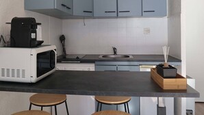 A modern kitchen with grey cabinets, a black countertop, a white microwave, a coffee maker, and a wooden box with a plant.