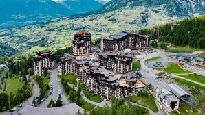 A mountainous resort with multiple high-rise buildings, roads, and a parking area.