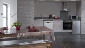 Une cuisine moderne avec une table à manger en bois, une machine à café, un grille-pain et un four à micro-ondes.