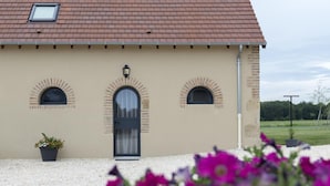 Un bâtiment à la façade beige, doté d’une porte sombre et de trois fenêtres en arc de cercle.