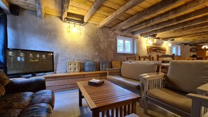 Un salon chaleureux avec un plafond en bois, un téléviseur et un canapé.