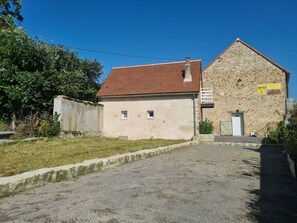 Un bâtiment avec un toit recouvert de tuiles rouges et une façade en pierre.