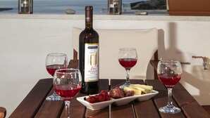 A table with a bottle of wine, glasses, and a plate of food on a terrace overlooking the sea. - Cycladic Sea view Mansion near the Castle (Νάξος)