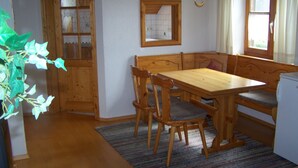 Ein Holztisch mit vier Stühlen, einer Bank und einem kleinen Kühlschrank.