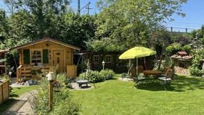 Eine Holzhütte mit Veranda, einem Esstisch mit Stühlen und einem gelben Sonnenschirm.