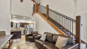 Un vaste espace de vie agrémenté d’un escalier en bois, d’un canapé en cuir et d’une table à manger.