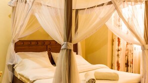 Een hemelbed met houten hoofdbord en een opgerolde handdoek op het bed.