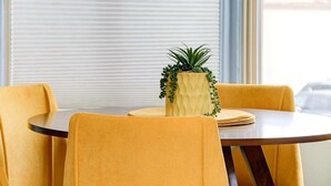A round table with a yellow cushion, a potted plant, and a folded tablecloth.