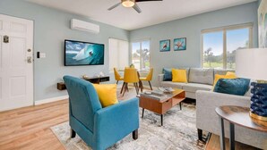 A living room with a TV, sofa, chairs, and a ceiling fan.