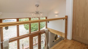 Una escalera de madera con barandilla de vidrio, un candelabro y vistas al exterior.