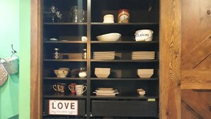 Un armario de cocina con repisas que contienen diferentes utensilios de cocina, incluyendo tazones, platos y un letrero que dice 'LOVE'.